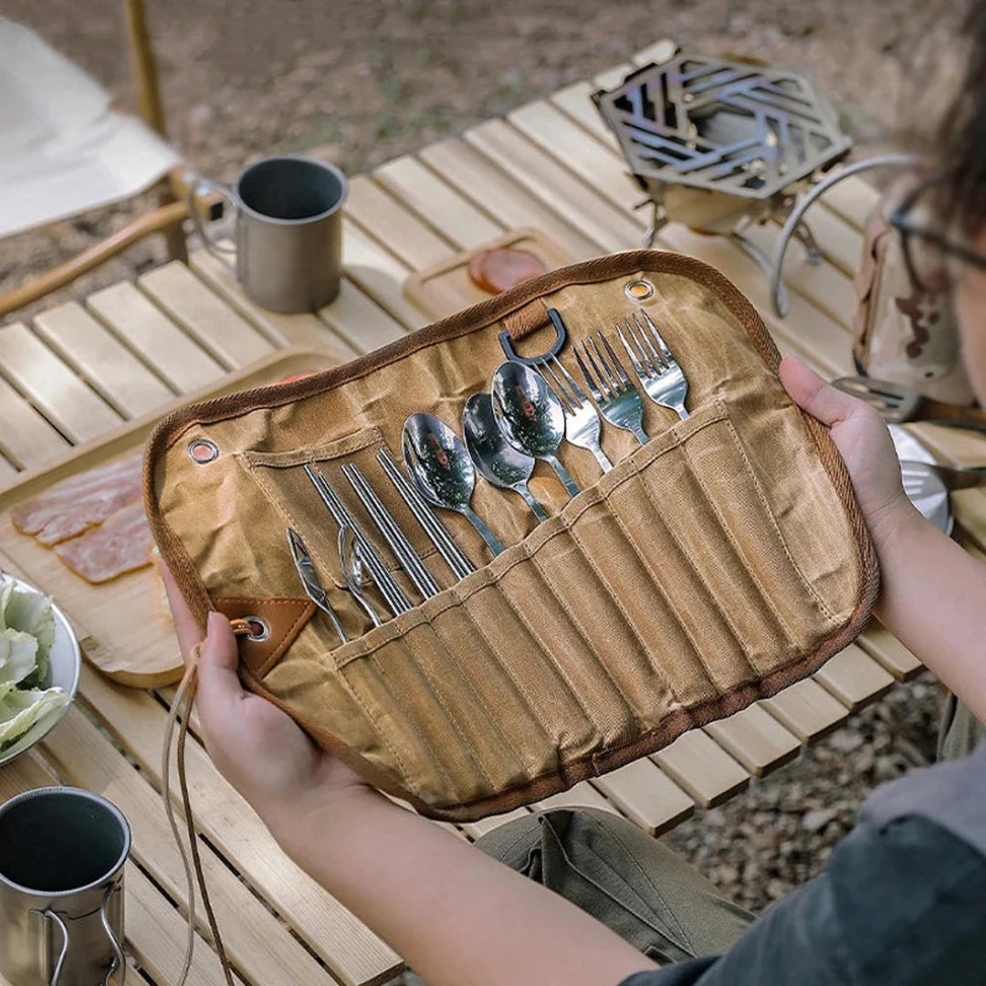 Camper holding the open cutlery roll at a campsite table