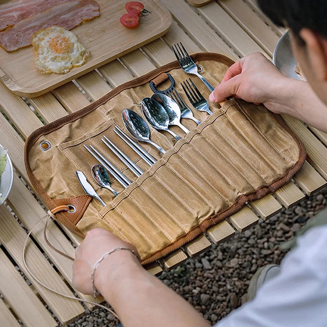 Cutlery roll open on a wooden camp table during a meal